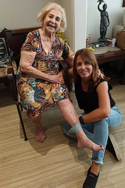 a fisioterapeuta jenny agachada ao lado de sua paciente, idosa, que está sentada em uma cadeira