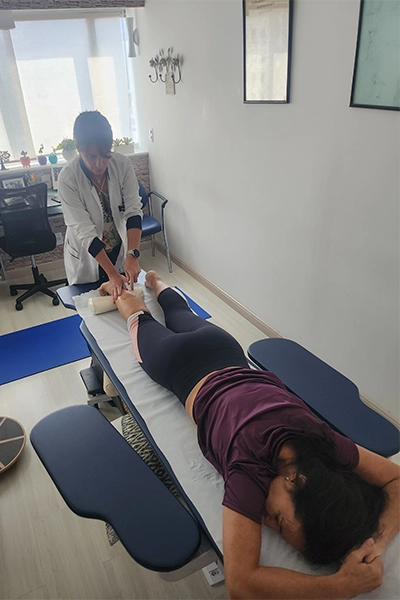 fisioterapeuta jenny realizando liberação miofascial na panturrilha de uma paciente, deitada